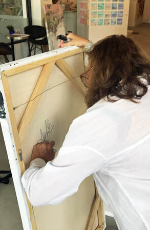 Anahi DeCanio signing artwork at Axiom Fine Art Gallery and Consulting